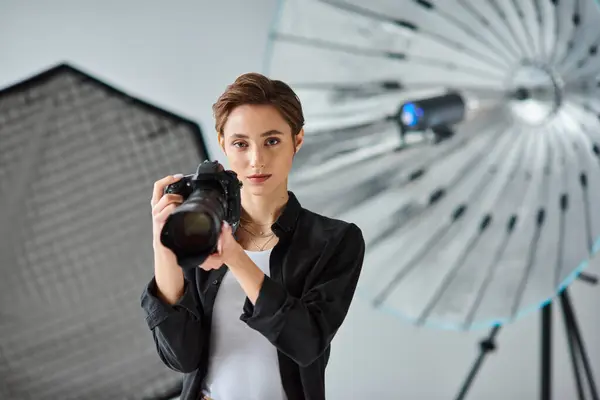 Beautiful female photographer in everyday attire looking at camera surrounded by her equipment — Stock Photo
