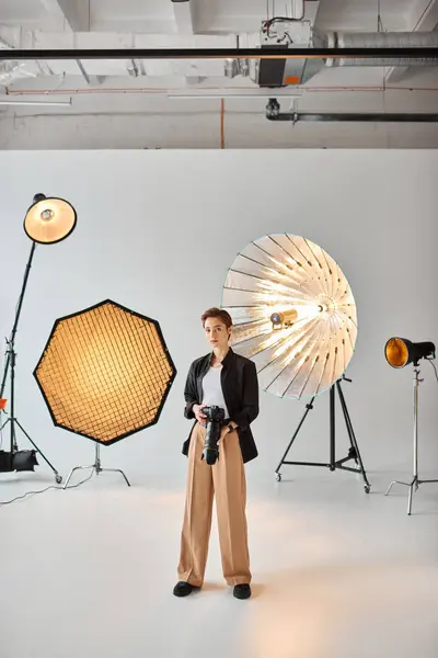 Attractive female photographer in everyday outfit looking at camera surrounded by her equipment — Stock Photo