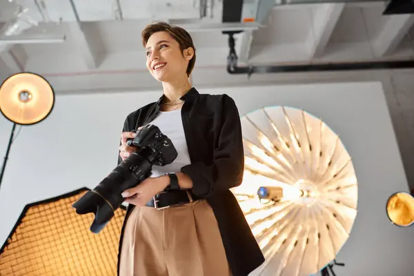Joyful female photographer in casual attire with camera in her hands smiling and looking away — Stock Photo