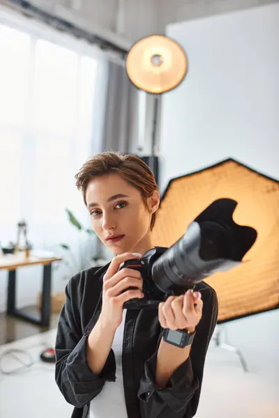 Beautiful short haired female photographer in casual attire looking at camera while at her studio — Stock Photo