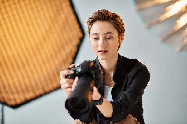 Junge hübsche Fotografin in lässiger Kleidung beim Betrachten der Fotos ihrer Kamera im Studio — Stockfoto