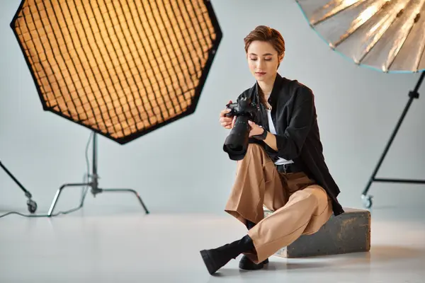 Giovane attraente fotografa donna in abbigliamento casual guardando le foto sulla sua macchina fotografica in studio — Foto stock