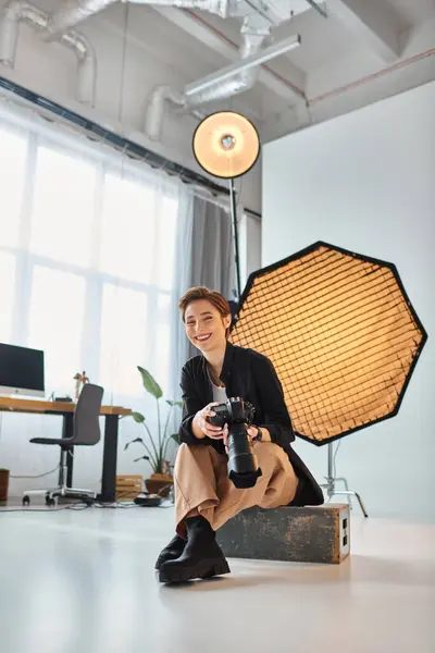 Happy attractive woman in casual outfit posing with her photography equipment in her studio — Stock Photo