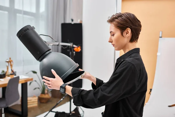 Gorgeous short haired female photographer in casual attire working with her equipment at studio — Stock Photo
