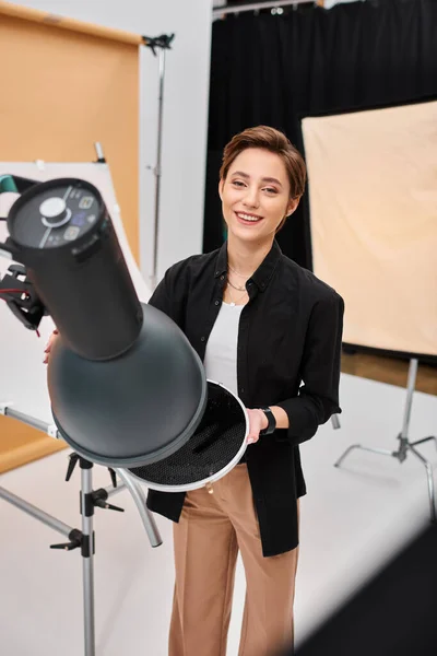 Короткошерста весела жінка з фотоапаратом, усміхненим весело на камеру в її студії — стокове фото