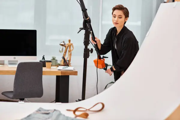 Belle jeune photographe féminine en vêtements décontractés travaillant avec son équipement au studio — Photo de stock