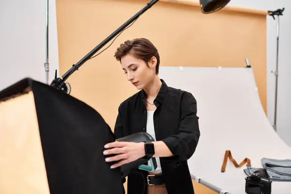 Charming young female photographer in everyday clothing working with her equipment at studio — Stock Photo