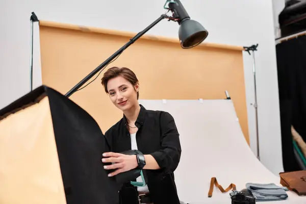 Stunning joyous woman with photography equipment smiling cheerfully at camera in her studio — Stock Photo