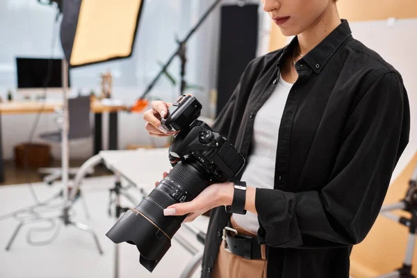 Cropped view of young female photographer in everyday attire working in her studio with equipment — Stock Photo