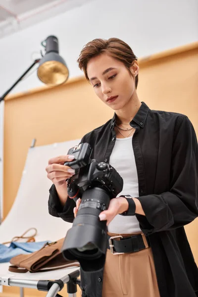 Pretty brunette female photographer in everyday clothing working with her equipment at studio — Stock Photo