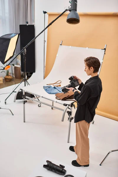 Junge brünette Fotografin in Alltagskleidung arbeitet mit ihrer Ausrüstung im Studio — Stockfoto