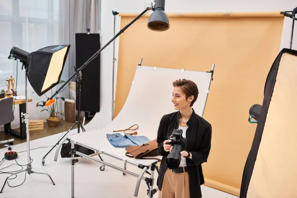 Щаслива чарівна жінка-фотограф в повсякденному одязі, що працює зі своїм обладнанням на студії — стокове фото