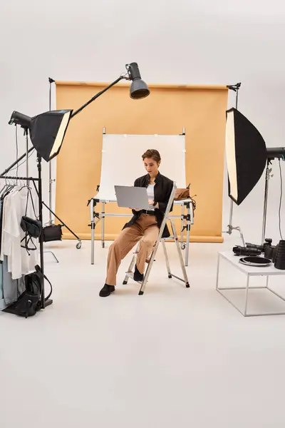 Bela fotógrafo de cabelos curtos sentado e retocando fotos em seu estúdio usando seu laptop — Fotografia de Stock