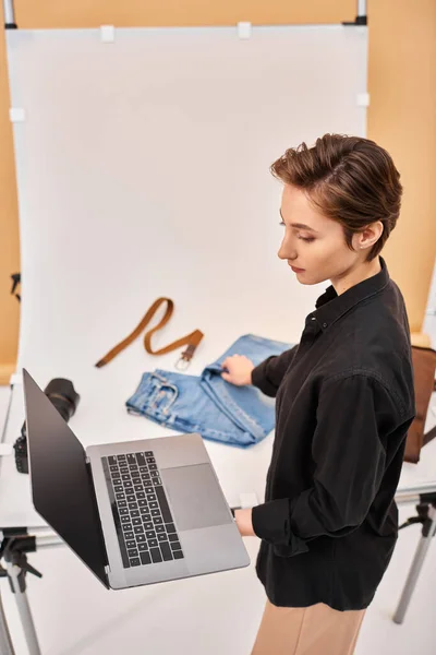 Attractive female photographer preparing for fashion photoshoot using her laptop and decorations — Stock Photo