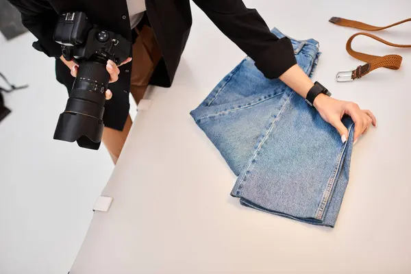 Cropped view of young female photographer preparing to make object photos of denim and brown belt — Stock Photo