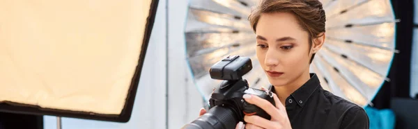 Beautiful concentrated woman in casual attire taking photos with her modern camera in her studio — Stock Photo