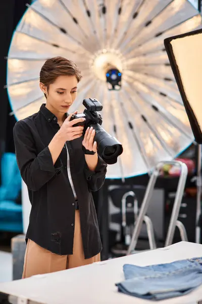 Bella donna dai capelli corti in abbigliamento casual scattare foto con la sua fotocamera moderna nel suo studio — Foto stock
