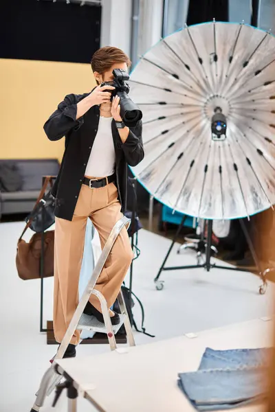 Mujer joven de buen aspecto en traje casual tomar fotos con su cámara moderna en su estudio - foto de stock