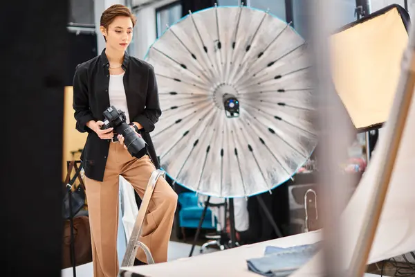 Gorgeous focused female photographer holding camera and prepearing to take photos in her studio — Stock Photo