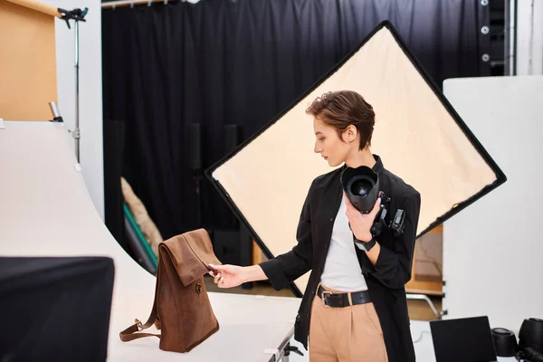 Fotógrafa feminina muito talentosa se preparando para tirar fotos de mochila de couro marrom em estúdio — Fotografia de Stock