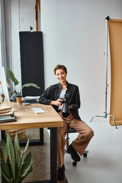 Alegre encantador fotógrafo feminino sorrindo para a câmera enquanto trabalhava em suas fotos em estúdio — Fotografia de Stock