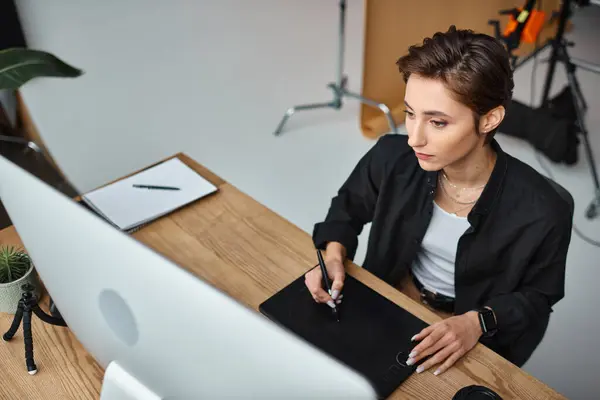 Beautiful short haired female designer in casual attire working on her project on drawing tablet — Stock Photo