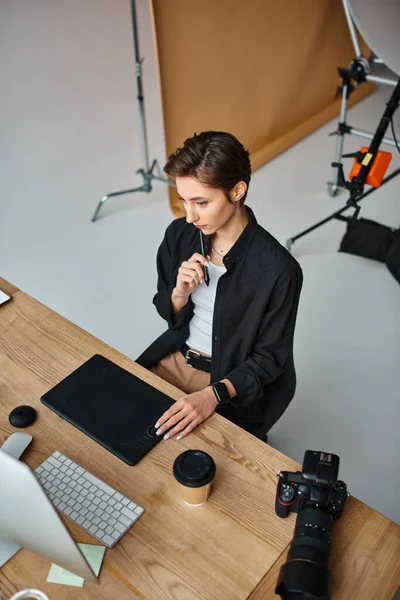 Encantadora diseñadora femenina de pelo corto en traje casual trabajando en su proyecto en la tableta de dibujo - foto de stock