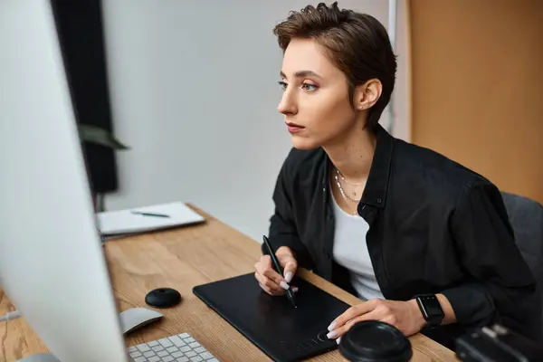 Appealing short haired female designer in casual attire working on her project on drawing tablet — Stock Photo