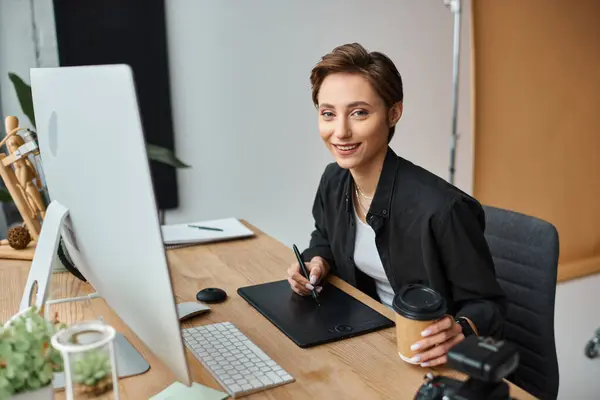 Cheerful short haired female designer in casual attire working on her project on drawing tablet — Stock Photo