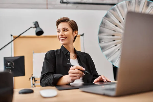 Joyful professional female designer in casual attire working with her drawing tablet in studio — Stock Photo