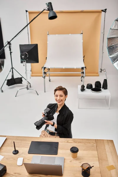 Mulher profissional alegre em traje casual sorrindo para a câmera trabalhando em seu local de trabalho em estúdio — Fotografia de Stock