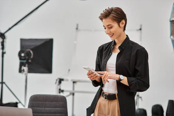 Merry young female photographer with short hair making stories for her social media in her studio — Stock Photo
