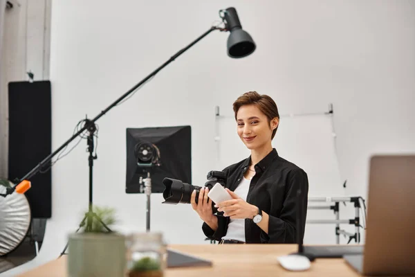 Jolly woman with smartphone in hands looking happily at camera while working in photo studio — Stock Photo
