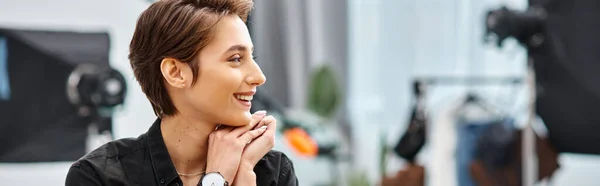 Joyous young professional female photographer in casual attire smiling and looking away, banner — Stock Photo