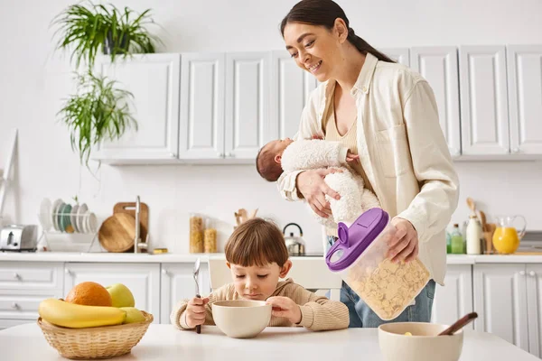 Alegre atraente mãe desfrutando de café da manhã com sua criança e filhos recém-nascidos, parentalidade moderna — Fotografia de Stock