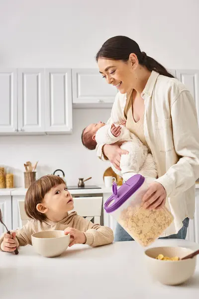 Joyful attractive mother enjoying breakfast with her toddler and newborn sons, modern parenting — Stock Photo