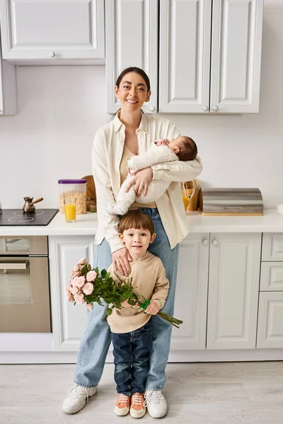 Любляча весела сім'я в домашньому вбранні позує з квітковим букетом під час перебування на кухні, сучасне батьківство — стокове фото