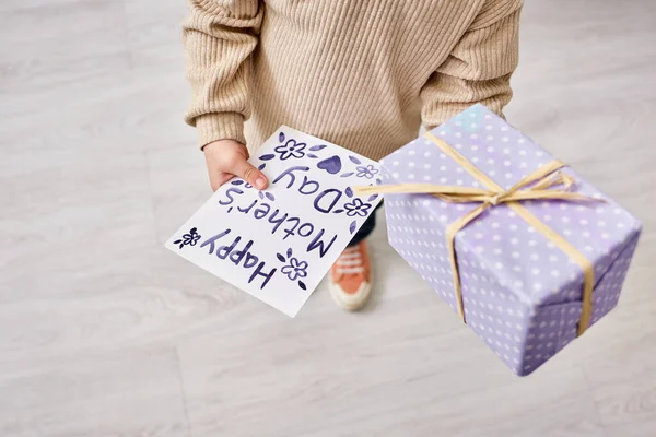 Cropped view of toddler boy in casual cozy attire holding present and postcard on Mothers day — Stock Photo