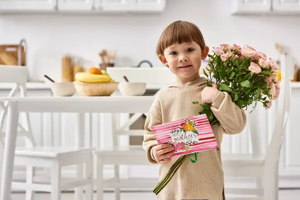Alegre lindo niño posando con tarjeta de felicitación y ramo de hermosas flores, Día de las Madres - foto de stock