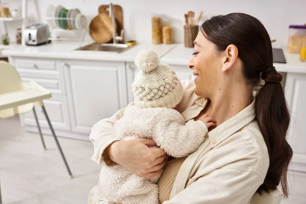 Attraente donna felice in accogliente homewear posa con il suo bambino neonato carino, genitorialità moderna — Foto stock