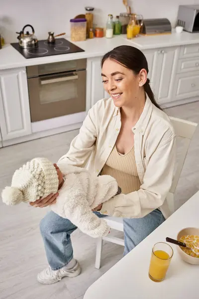 Jolly attractive woman in homewear holding her cute baby boy during breakfast, modern parenting — Stock Photo