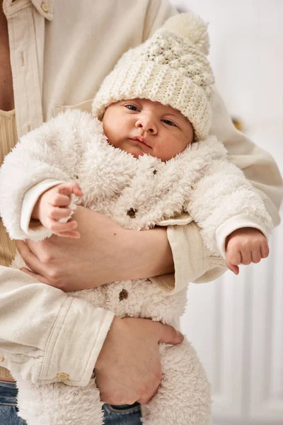 Adorable newborn baby in warm comfortable attire in hands of his loving mother, modern parenting — Stock Photo