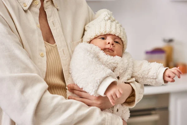 Adorable newborn baby in warm comfortable outfit in hands of his caring mother, modern parenting — Stock Photo