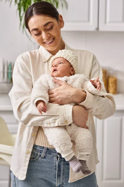 Attraktive lustige Frau in bequemer Homewear posiert mit ihrem netten neugeborenen Jungen, moderne Elternschaft — Stockfoto