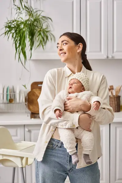 Attractive merry woman in comfy homewear posing with her cute newborn baby boy, modern parenting — Stock Photo