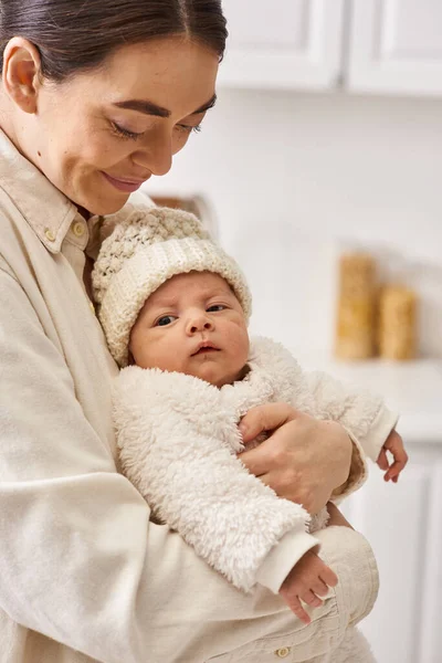 Attractive joyous woman in comfy homewear posing with her cute newborn baby boy, modern parenting — Stock Photo