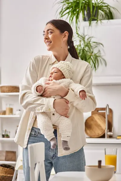Cheerful pretty woman in casual homewear posing with her cute newborn baby boy, modern parenting — Stock Photo
