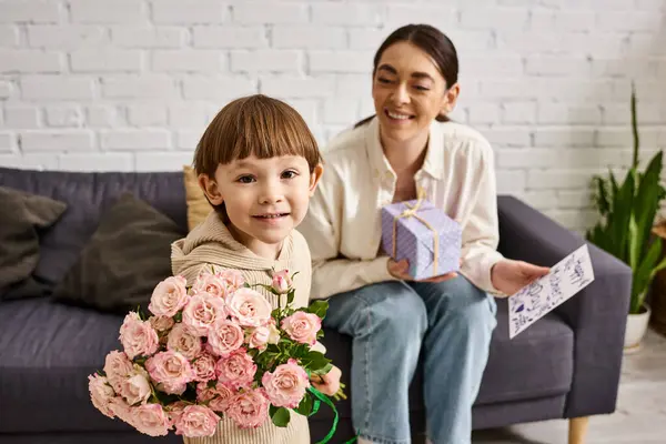 Adorable toddler boy giving his mom present and postcard with flower bouquet on Mothers day — Stock Photo