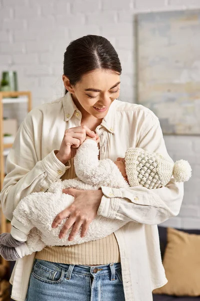 Attraente madre allegra in casa tenendo amorevolmente il suo bambino appena nato, genitorialità moderna — Foto stock