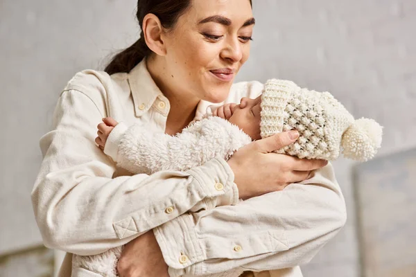 Appealing cheerful mother in homewear holding lovingly her newborn baby boy, modern parenting — Stock Photo